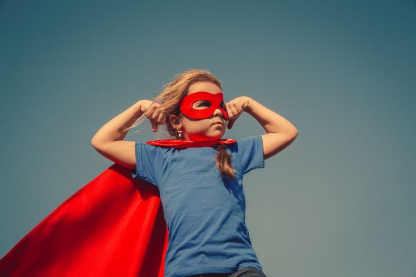 Kid with cape & super hero mask, in a super hero pose